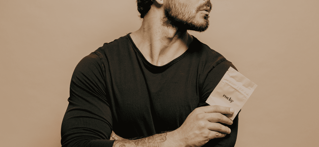 A man holding a beige package with the text 'rocky' on it.