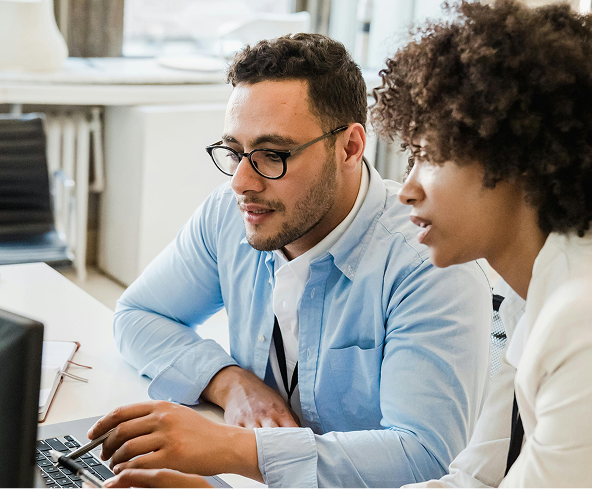 Two co-workers looking at a screen and discussing.